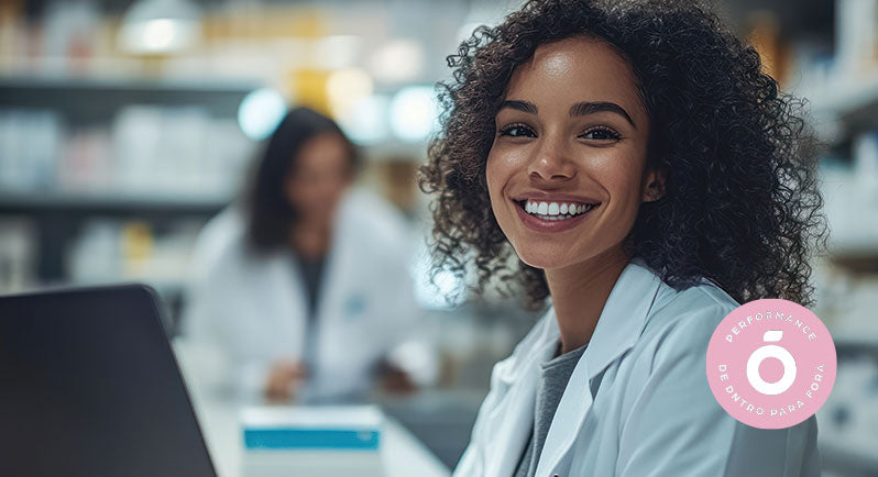 Mulher sorridente com jaleco branco em ambiente de farmácia ou laboratório, representando confiança, profissionalismo e saúde. No canto da imagem, selo rosa “Performance de DNTRO para Fora”, reforçando a credibilidade científica por trás dos suplementos naturais da marca.